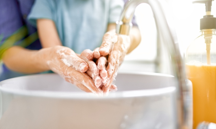 A parents helps a child wash hands.
