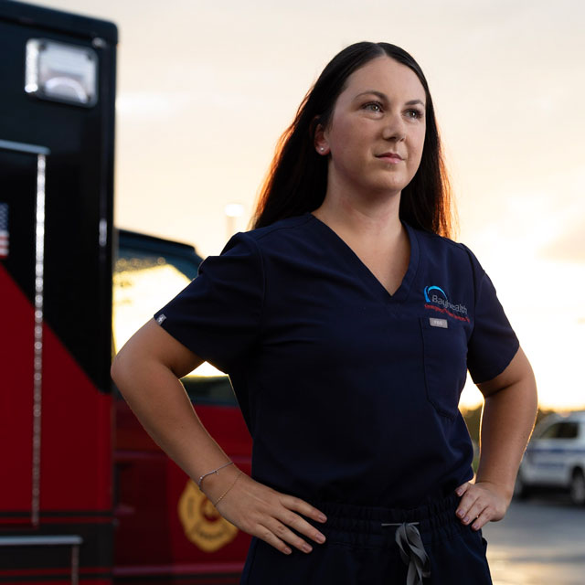Nurse standing outside of emergency room in front of an ambulance