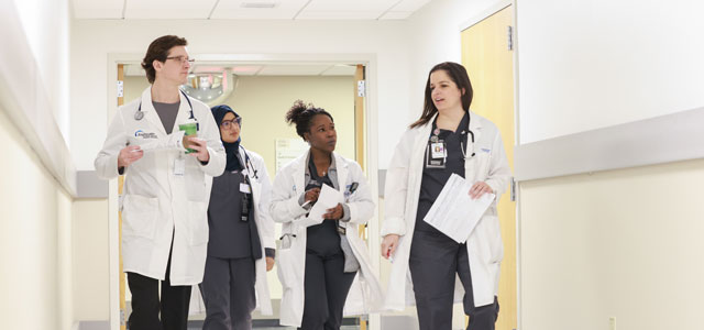 Internal medicine residents conversing in a hospital hall way.